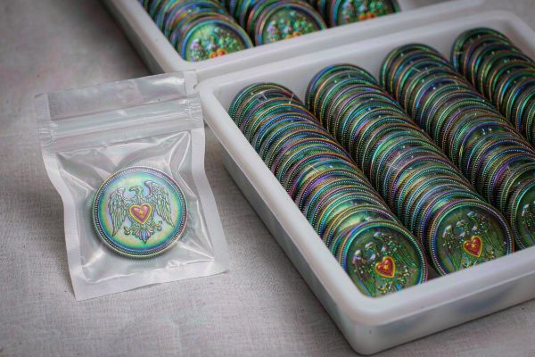 A single custom challenge coin beside a large bulk tray, showing minimum order versus bulk