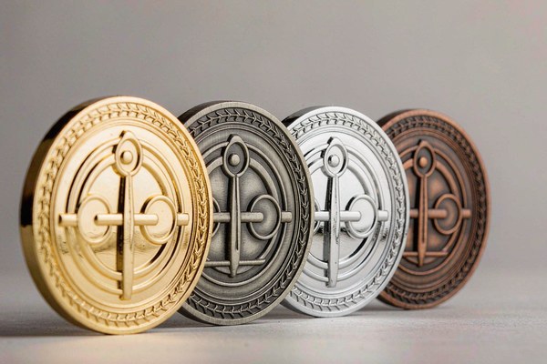 Custom challenge coin metal plating options displaying shiny gold, antique silver, polished nickel, and bronze finishes
