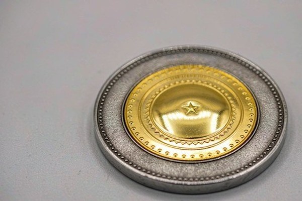 Dual plated custom challenge coin featuring a polished shiny gold center emblem on an antique silver textured base