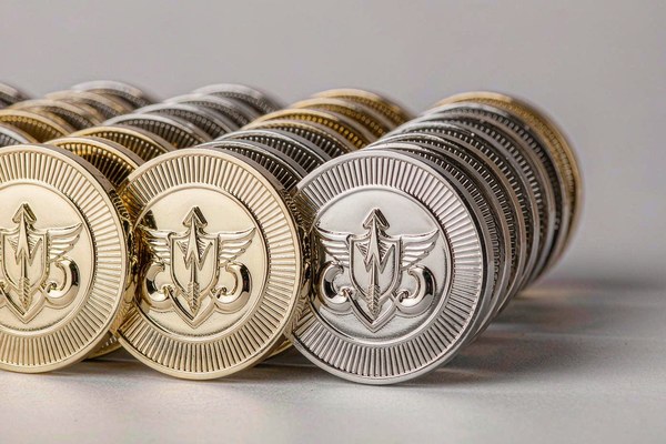 Rows of custom challenge coins arranged to show increasing order quantity from a small batch to a bulk run