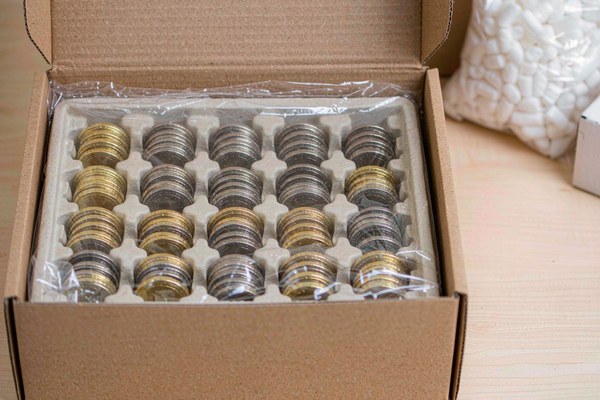 Finished custom challenge coins packed in protective trays inside a shipping carton